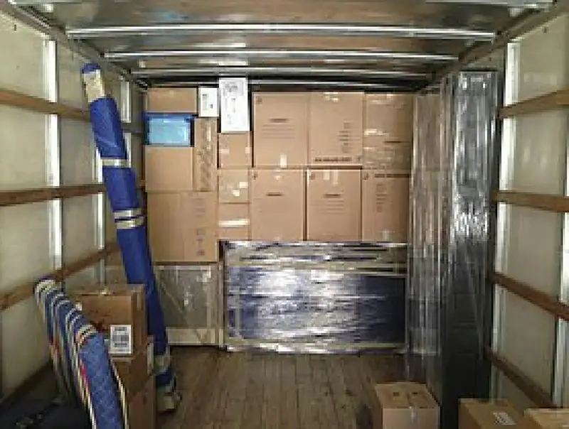 Laderaum eines Transporters mit gestapelten Kartons und in Folie gewickelten Möbeln