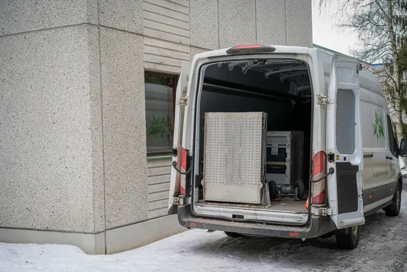 Weißer Transporter mit offener Ladefläche vor einem Wohnhaus